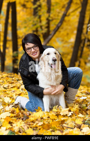 Schönen Lächeln brünette Frau mit Golden Retriever im Herbst Park. Stockfoto