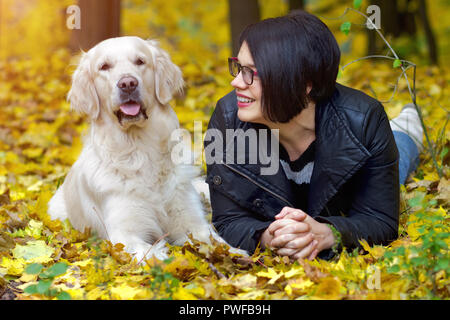 Schönen Lächeln brünette Frau mit Golden Retriever im Herbst Park. Stockfoto