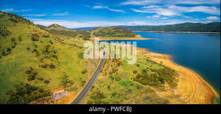 Landstraße, die durch grüne Hügel und See - malerische Antenne panorama Stockfoto