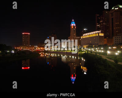 COLUMBUS, Ohio - 15. Juli 2018: Die Scioto River an der Skyline von Columbus, Ohio über den von Bäumen gesäumten, Grasbewachsenen. beleuchtete Wege und sidewal Stockfoto