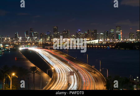 Die nächtliche Skyline von Miami als von oben der Verkehr von MacArthur Causeway, einer stark befahrenen Brücke Miami mit Miami Beach gesehen Stockfoto