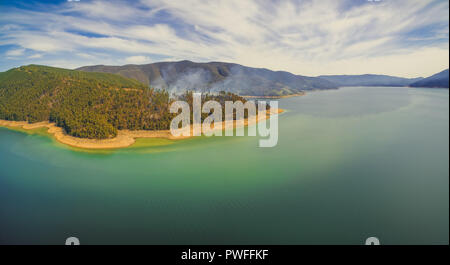 Antenne Panorama der aufsteigenden Rauch aus Wald am schönen Seeufer Stockfoto