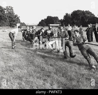 1967, Tauziehen Wettbewerb in einer Wiese an einem englischen Dorffest. Bild zeigt ein Team von acht Männer ziehen an einem Seil so hart, wie Sie in einer Richtung in einem Test der körperlichen Stärke gegen die gegnerische Mannschaft ziehen. Stockfoto