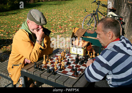 Zwei Männer spielen Schach im Freien in einem Park auf einem Holztisch Stockfoto