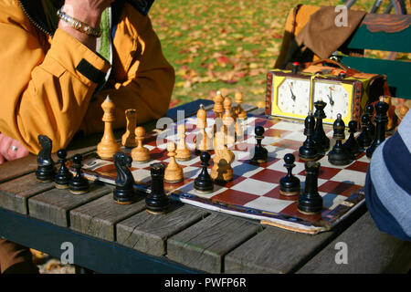Zwei Männer spielen Schach im Freien in einem Park auf einem Holztisch. Close Up. Kann nur Hände gesehen werden. Stockfoto