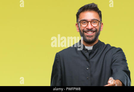 Nach spanischer katholischer Priester Mann über isolierte Hintergrund lächelt freundlich mit Handshake als Ansage und einladend. Erfolgreiches Business. Stockfoto