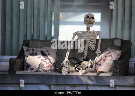 Skelett entspannt auf der Veranda eines Hauses als Halloween Dekoration als Feier der einen Fall Urlaub angezeigt. Stockfoto