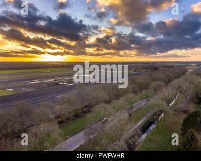 Luftaufnahme über Felder auf holländischen Landschaft unter schönen Sonnenuntergang im Winter in der Provinz Groningen, Niederlande Stockfoto