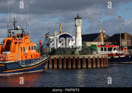 Besetzt Kirkwall Hafen in Kirkwall, Orkney, Schottland, auf einer frühen sonnigen Morgen. Ein Rettungsboot, Fähre und Schiff sind in der Nähe des Leuchtturms angedockt. Stockfoto