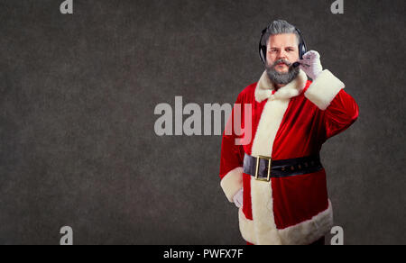 Santa Claus in einem Headset Call Center Betreiber auf einem Copyspace Hintergrund. Stockfoto