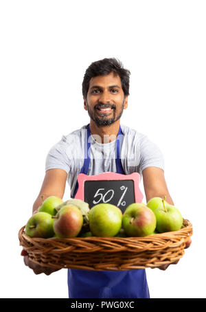 Indische lächelnd Supermarkt Mitarbeiters, organische apple Korb mit 50 Prozent Rabatt Zeichen als frischen und gesunden Konzept isoliert auf weißem Stockfoto