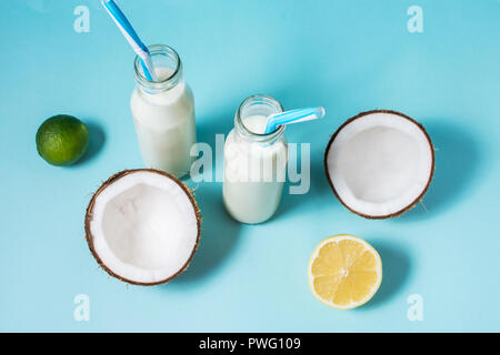 Kokosöl vegane Milch coctail in der Flasche auf blauem Hintergrund. Stockfoto