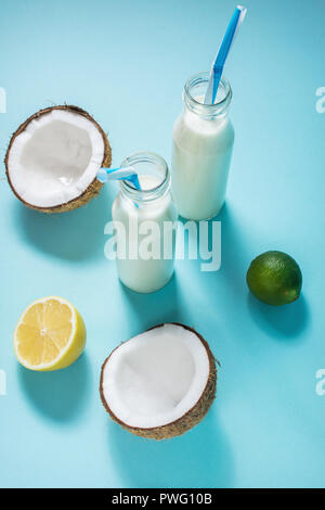 Kokosöl vegane Milch coctail in der Flasche auf blauem Hintergrund. Stockfoto