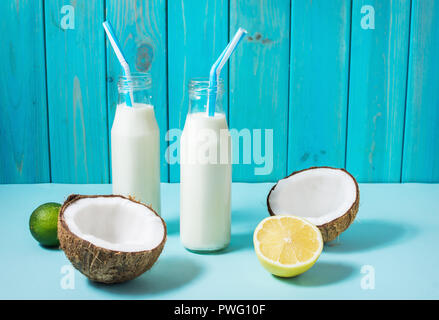 Kokosöl vegane Milch coctail in der Flasche auf blauem Hintergrund. Stockfoto