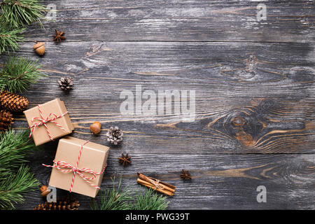 Weihnachtsgeschenke im rustikalen Stil. Zwei Geschenkboxen mit Zimtstangen, Tannenzapfen, Anis Sterne und Kiefer Filialen auf Holztisch. Ansicht von oben. Stockfoto