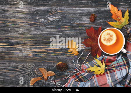 Herbst heißen Tee mit Zitrone dekoriert gelbe und rote Blätter, und karierten Schal auf Holztisch. Ansicht von oben mit der Kopie. Stockfoto