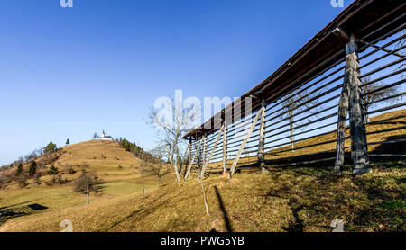 Kirche auf einem Hügel Sv. Jakob in Slowenien Landschaft. Alte hayrack und Fußweg führt zum Sv. Jakob Hügel mit Kirche St. James oben, über Ljubl Stockfoto