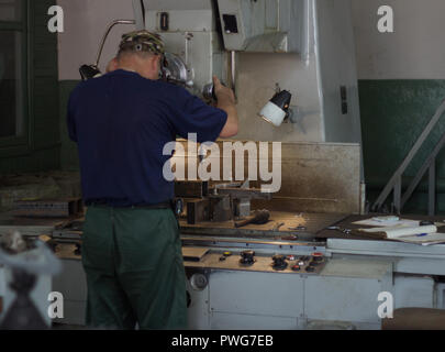 Ein Mann spezialisiert sich ein Bohrer bohren der Löcher auf eine Bohrmaschine in einem metallischen Werkstück, ein kleines Unternehmen, private Werkstatt, Bank, individuelle Stockfoto