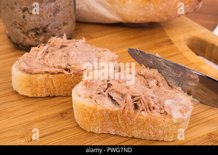 Zwei selbstgemachte Rillettes Französisch verbreitet aus Schweinefleisch auf ein Baguette Brot und Messer Verbreitung der Rillettes Stockfoto