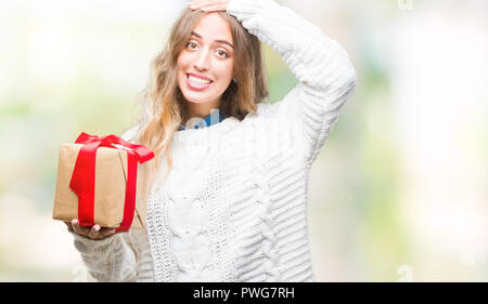 Schöne, junge blonde Frau mit Geschenk über isolierte Hintergrund mit Hand betonte am Kopf, mit Scham und Überraschung Gesicht schockiert, wütend und frustra Stockfoto