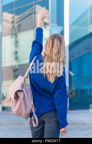 Die Frau stand mit dem Rücken zur Kamera im Büro Gebäude aus Glas, die Hand nach oben Stockfoto