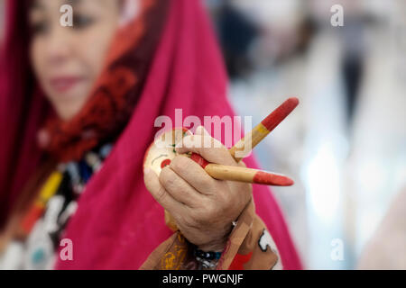 Eine usbekische Frau in traditioneller Kleidung aus der Region Surkhandarya nahe der südlichen Grenze zu Tadschikistan, die Holzlöffel für rhythmische Percussion verwendet, um den „Raqs-e Koshik“ oder den Löffeltanz in Usbekistan zu begleiten Stockfoto