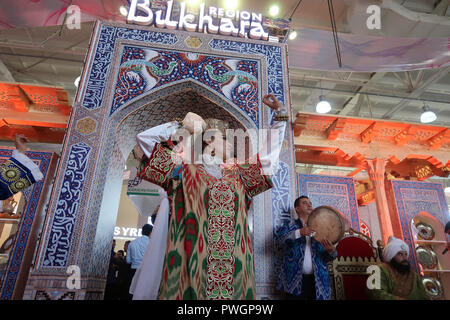 Junge usbekische Frau trägt traditionelle Satin-Stoff reich bestickt mit tanz mit goldenen Fäden auf der Taschkent International Tourism Fair (TITF) In der Stadt Taschkent Hauptstadt von Usbekistan Stockfoto