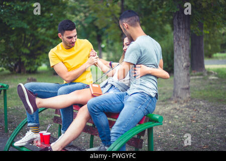 Freunde sitzen auf einer Bank im Park, Witze und Spaß haben Stockfoto