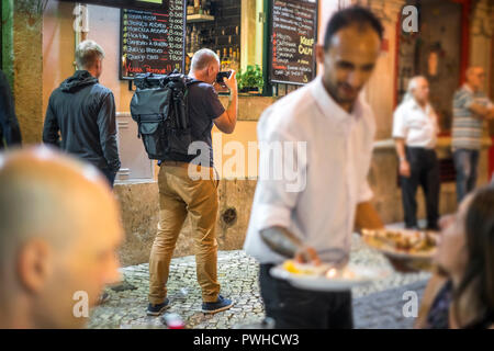 Fotograf Fotos von belebten Straßen mit Restaurants in Alfama, Lissabon, Portugal Stockfoto