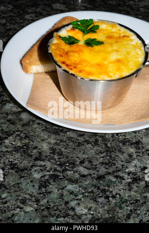 Gebratene Pilze, Huhn und Käse, der im Rahmen einer cremigen Soße in Metallschale auf einem steinernen Tisch, selektive konzentrieren. Stockfoto