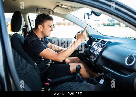 Wütende Menschen gestikuliert mit der Hand aus dem Fenster während der Fahrt. Verrückte Fahrer aus dem Auto bei Sonnenaufgang kreischen. Stress, Traffic rush hour, ängstlich, Wahnsinn, Stockfoto