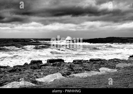 Porthcawl an einem stürmischen Tag mit Wellen, die auf Felsen, in Schwarzweiß gedreht, South Wales Stockfoto