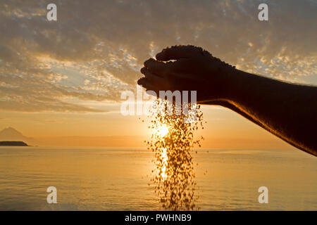Konzept vorbei. Mann Hand gießen Sand auf den Sonnenaufgang Hintergrund Stockfoto
