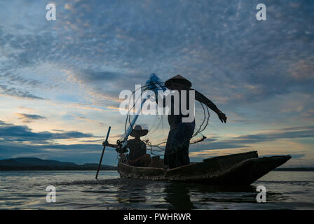 Fischer, die mit Netzen Fische am Bangpra See bei Sonnenaufgang Zeit zu fangen. Stockfoto