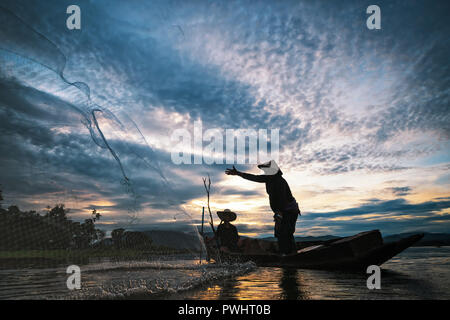Fischer, die mit Netzen Fische am Bangpra See bei Sonnenaufgang Zeit zu fangen. Stockfoto