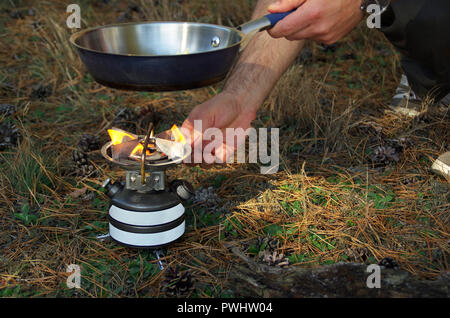 Flamme unter der Pfanne in der Hand auf den Herd. Inbetriebnahme des Brenners outdoor. Stockfoto