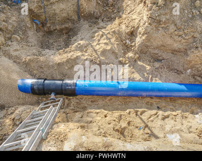 Reparatur der unterirdischen Wasserversorgung Pipeline. Kunststoff blau Röhren in graben zusammen mit Kunststoffrohren mit gemeinsamen und Schraube fl geschweißt Stockfoto