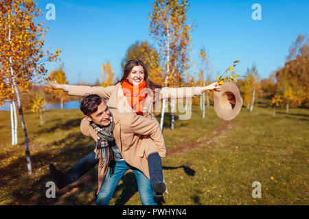 Junges Paar Spaziergänge im Herbst Wald. Mann, der seine Freundin Piggyback. Menschen, die Spaß im Freien Stockfoto