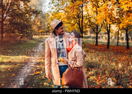 Junges Paar in Liebe Spaziergänge im Herbst Wald unter bunten Bäumen. Menschen umarmen und sprechen bei Sonnenuntergang Stockfoto