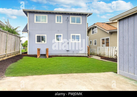 Blue Home Exterieur mit großen, vollständig eingezäunten Garten und gepflegten Rasen. Stockfoto