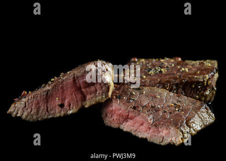 Medium Rindersteak. Mit Pfeffer gewürzt. Auf schwarz isoliert. Kopieren Sie Platz. Stockfoto