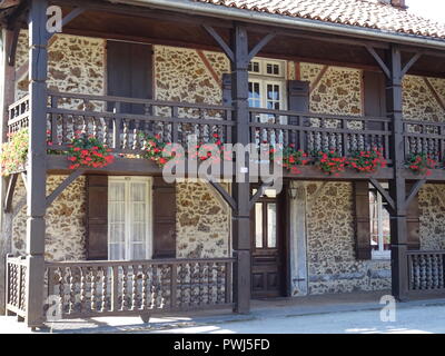 Alten, typischen Fassade aus Stein mit leuchtend roten Blumenkübel auf dem Balkon im Südwesten von Frankreich l Stockfoto