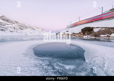 Der Bernina Express verkehrt neben dem gefrorenen Lago Bianco Berninapass Kanton Graubünden Engadin Schweiz Europa Stockfoto