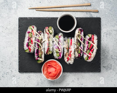 Vegane sushi Sandwich onigirazu mit Pilzen und Gemüse. Gesund essen Rezept und Idee. Bunte japan Sandwich onigirazu mit Rotkraut, Radieschen, Gurken, Pilze. Trend essen. Ansicht von oben Stockfoto