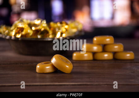 Gruppe der Acht ganze Caramel Cream candy butterscotch Vielzahl zwei im Fokus im alten Eisen Schale mit Restaurant im Hintergrund Stockfoto