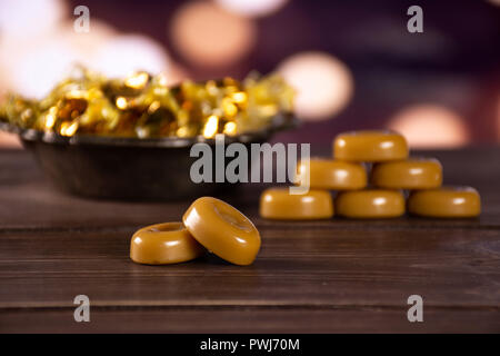 Gruppe der Acht ganze Caramel Cream candy butterscotch Vielzahl zwei im Fokus im alten Eisen Schale mit Licht in dunklen Hintergrund Stockfoto