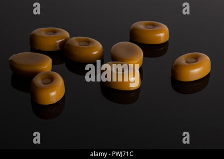 Gruppe der Acht ganze Caramel Cream candy butterscotch Vielfalt auf schwarzem Glas Stockfoto