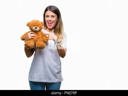 Junge schöne Frau mit teddybär Plüsch über isolierte Hintergrund sehr glücklich zeigte mit Hand und Finger Stockfoto