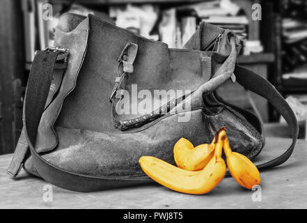 Alte wildleder Tasche und drei reife Bananen in Schwarz und Weiß Stockfoto