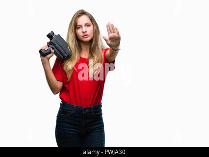 Junge hübsche blonde Frau Filmen verwenden vintage Kamera über isolierte Hintergrund mit der offenen Hand tun, STOP-Schild mit schweren und zuversichtlich expressio Stockfoto